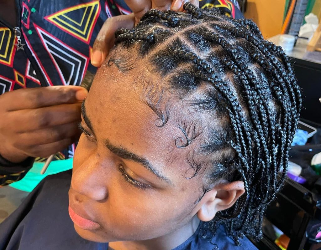 A close-up of neatly braided hair, showcasing intricate patterns and shiny, well-maintained strands in a cozy salon setting.