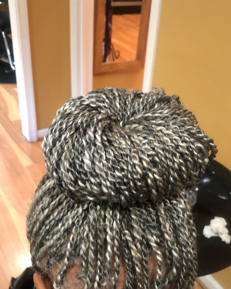 A close-up of a stylish bun made of intricately twisted hair, showcasing a mix of dark and light strands.